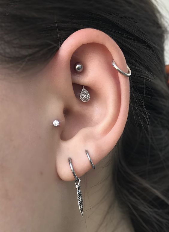 O piercing no rook ganha mais atenção, enquanto o ponto de luz no tragus e a argola na helix apenas complementam / Reprodução: Pinterest