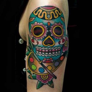 Braço tatuado com caveira mexicana colorida